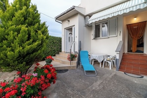 Il s’agit d’une propriété résidentielle dotée d’un patio, d’un fauteuil bleu, d’une petite table avec des chaises et d’un escalier menant à l’entrée.