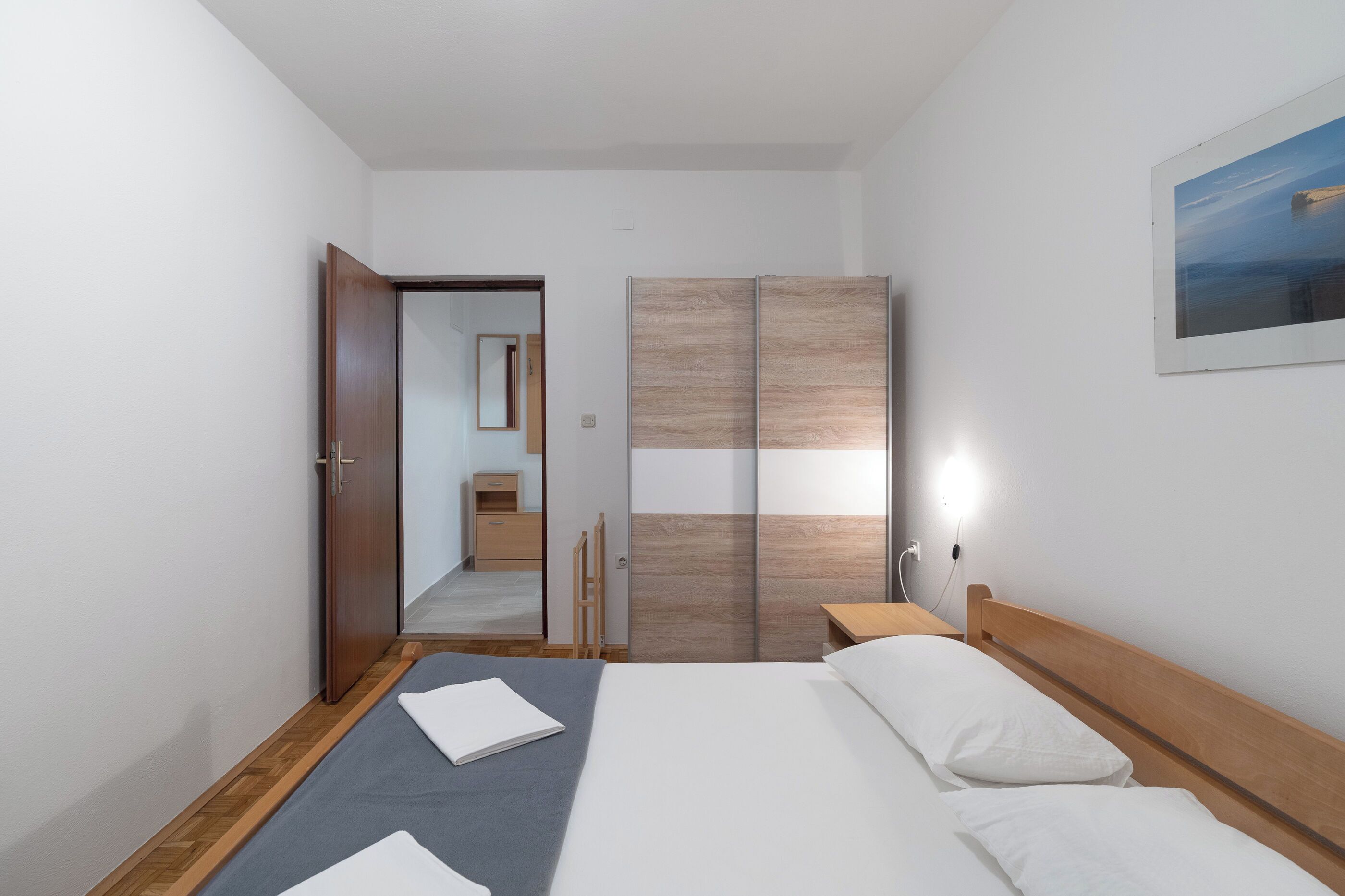 Une chambre d’hôtel avec un lit, des tables de chevet, une armoire, un miroir et un tableau au mur.