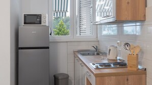 Una cocina compacta con microondas integrado, un lavamanos y una encimera de madera.