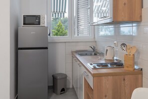 A compact kitchen with a built-in microwave, a sink, and a wooden countertop. - Apartments Pere (Povljana)