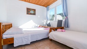 A bedroom with two beds, a ceiling fan, a window with curtains, and a painting on the wall. - Apartment Doktor (Trogir)