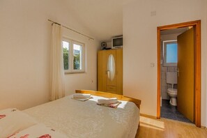Ein Schlafzimmer mit Bett, Kleiderschrank, Fernseher und einem durchgegangenen Tür erkennbaren Badezimmer.