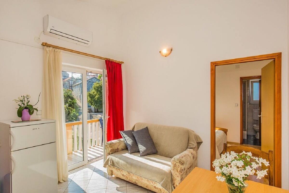 Une pièce comprenant un canapé, une petite table avec un vase, un miroir et un appareil de climatisation.