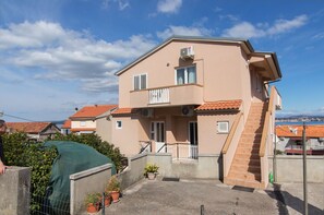 Ein zweistöckiges Gebäude mit Balkon, Treppe und Meerblick.
