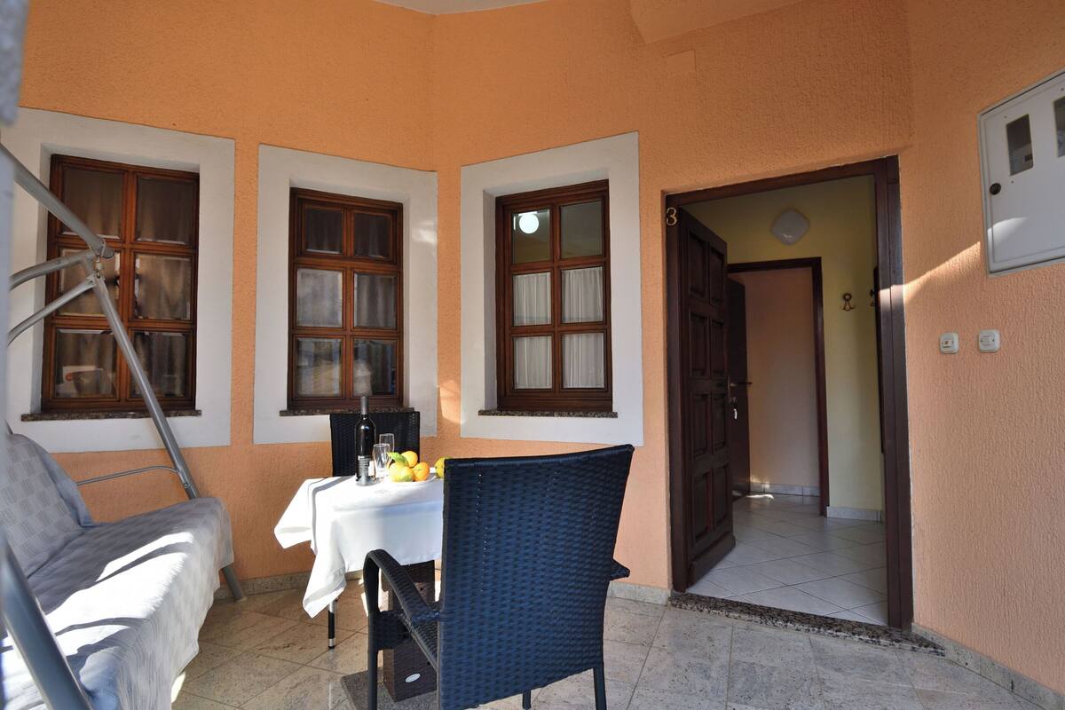 Un petit espace patio avec une table dressée pour deux personnes, une chaise et une échelle appuyée contre le mur.