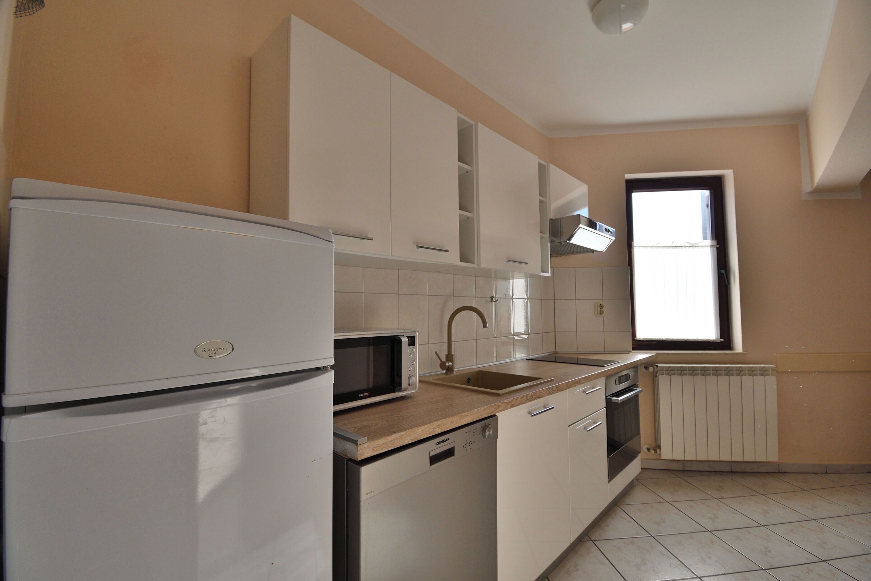 A kitchen with white cabinets, a microwave, a sink, and a window.