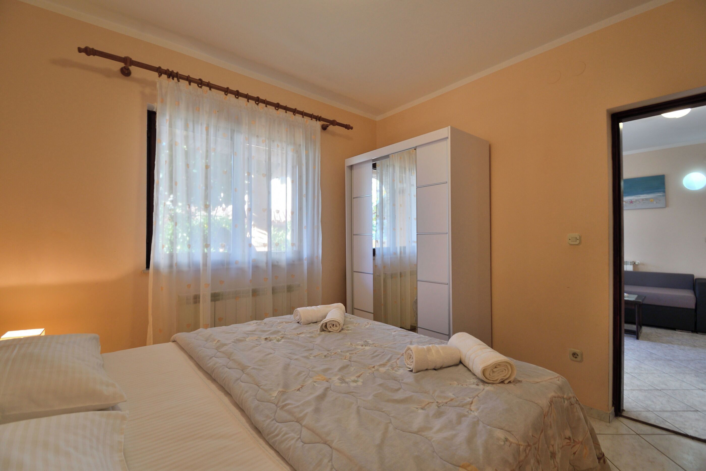 A bedroom with a bed, a wardrobe, and a bathroom visible through an open door.