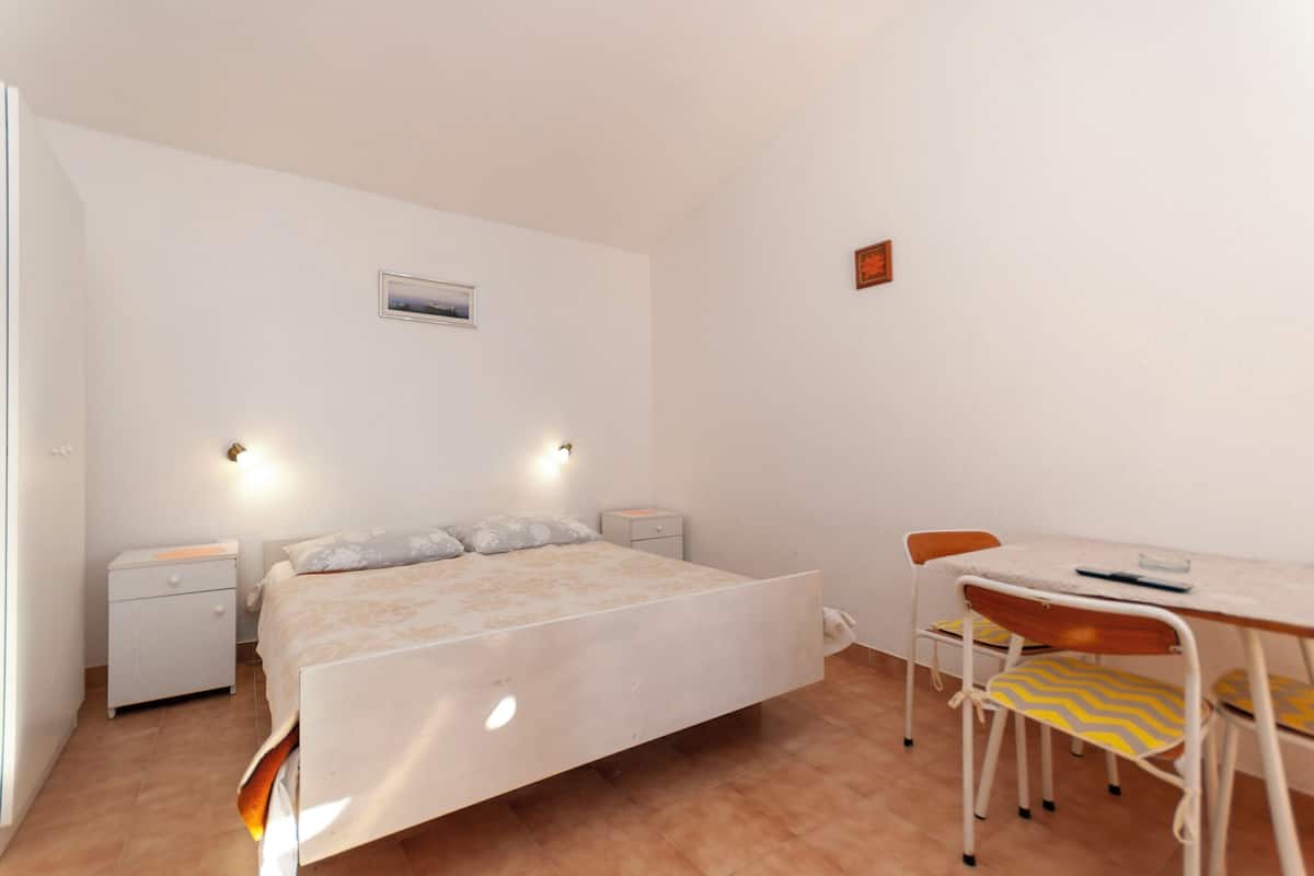 Een slaapkamer met een bed, nachtkastjes, een bureau en stoelen.