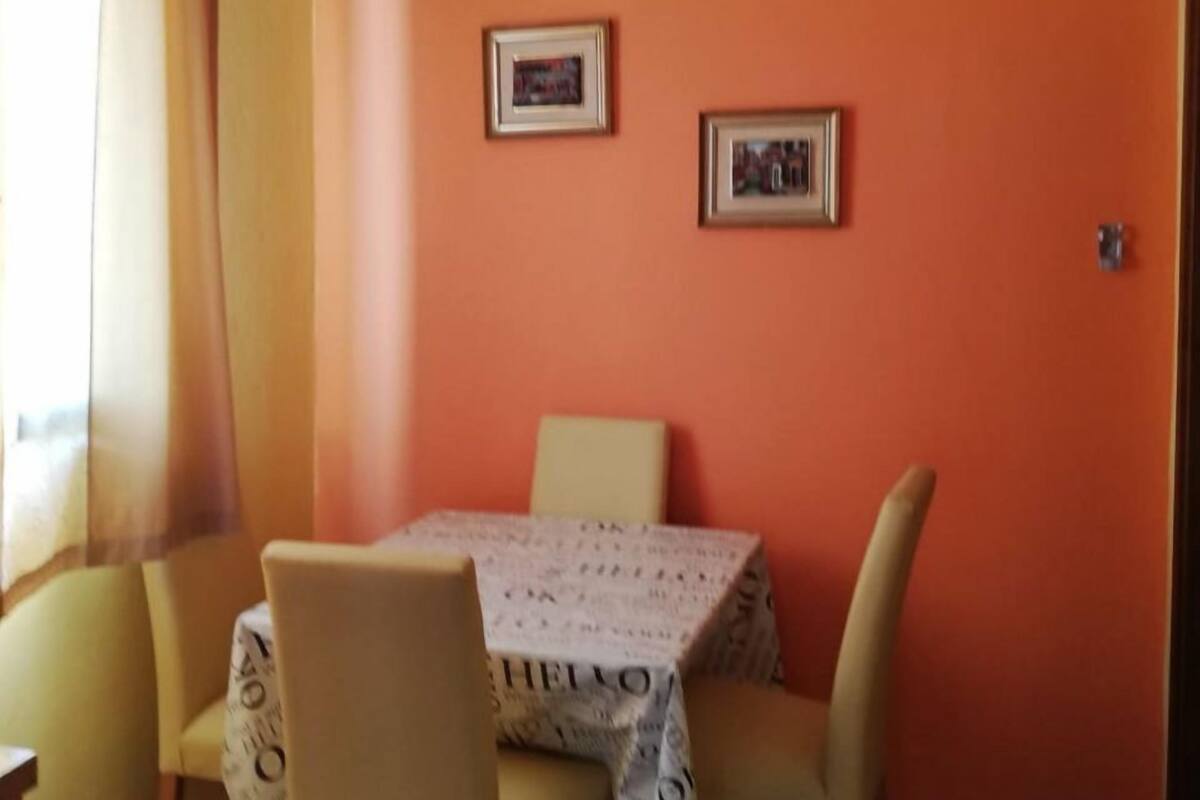 A dining area with a table and four chairs, an air conditioning unit on the wall, and two framed pictures.
