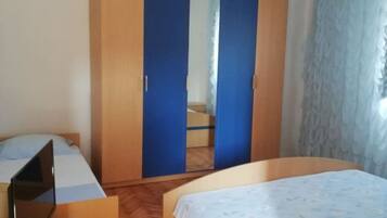Ein Schlafzimmer mit zwei Betten, einem Holzschrank und einem Schreibtisch mit einem Laptop.