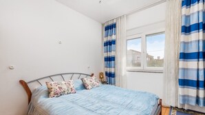 A bedroom with a bed, two pillows, a window, and curtains. - Apartments Masa (Povljana)