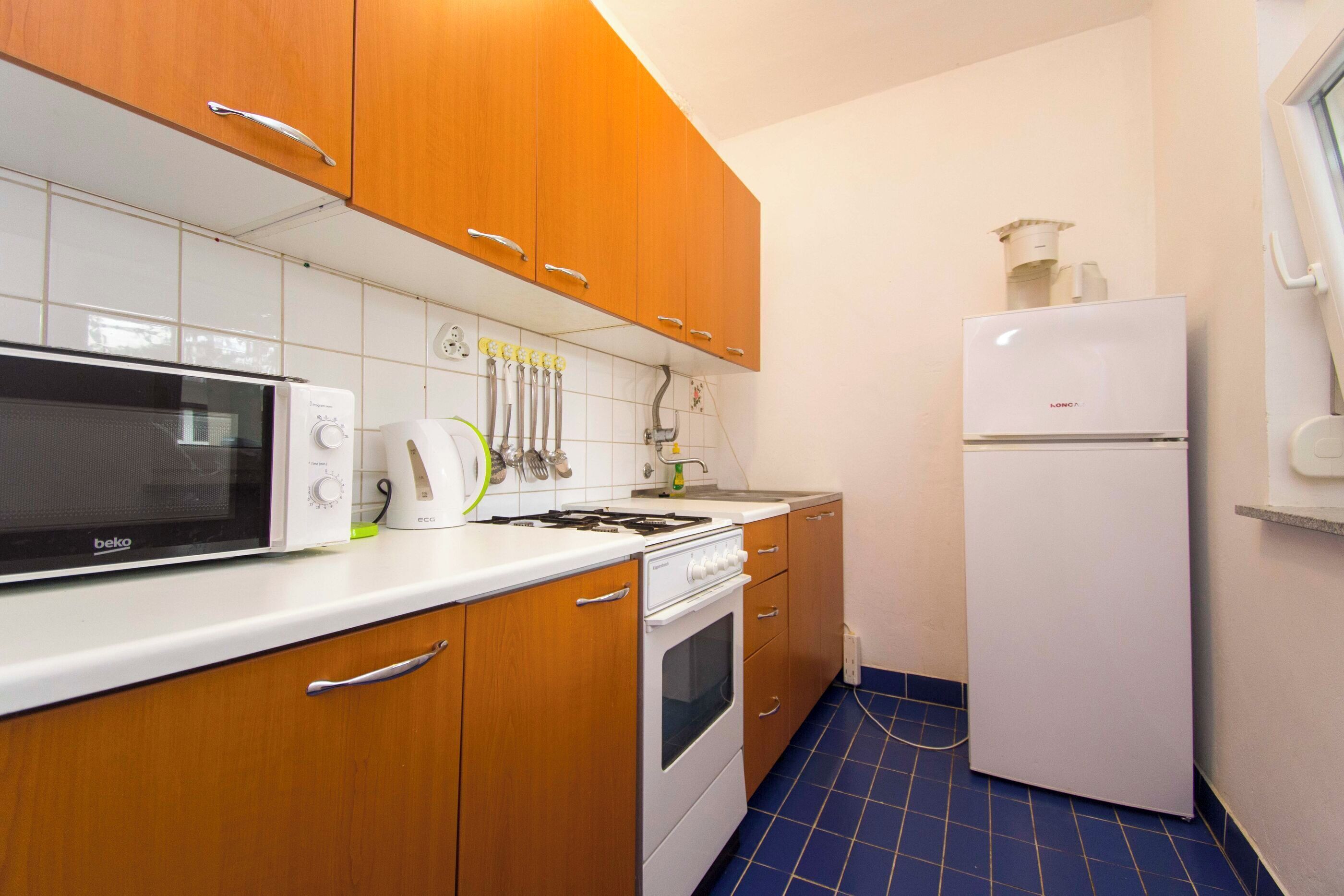 Una cucina con mobili in legno, un forno a microonde bianco, un fornello e un frigorifero bianco.