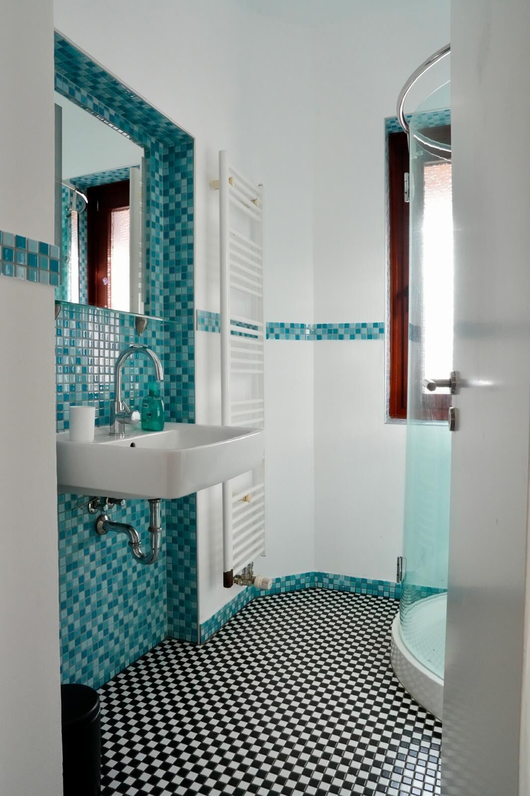A bathroom with a checkered floor, a white sink, and a mirror.