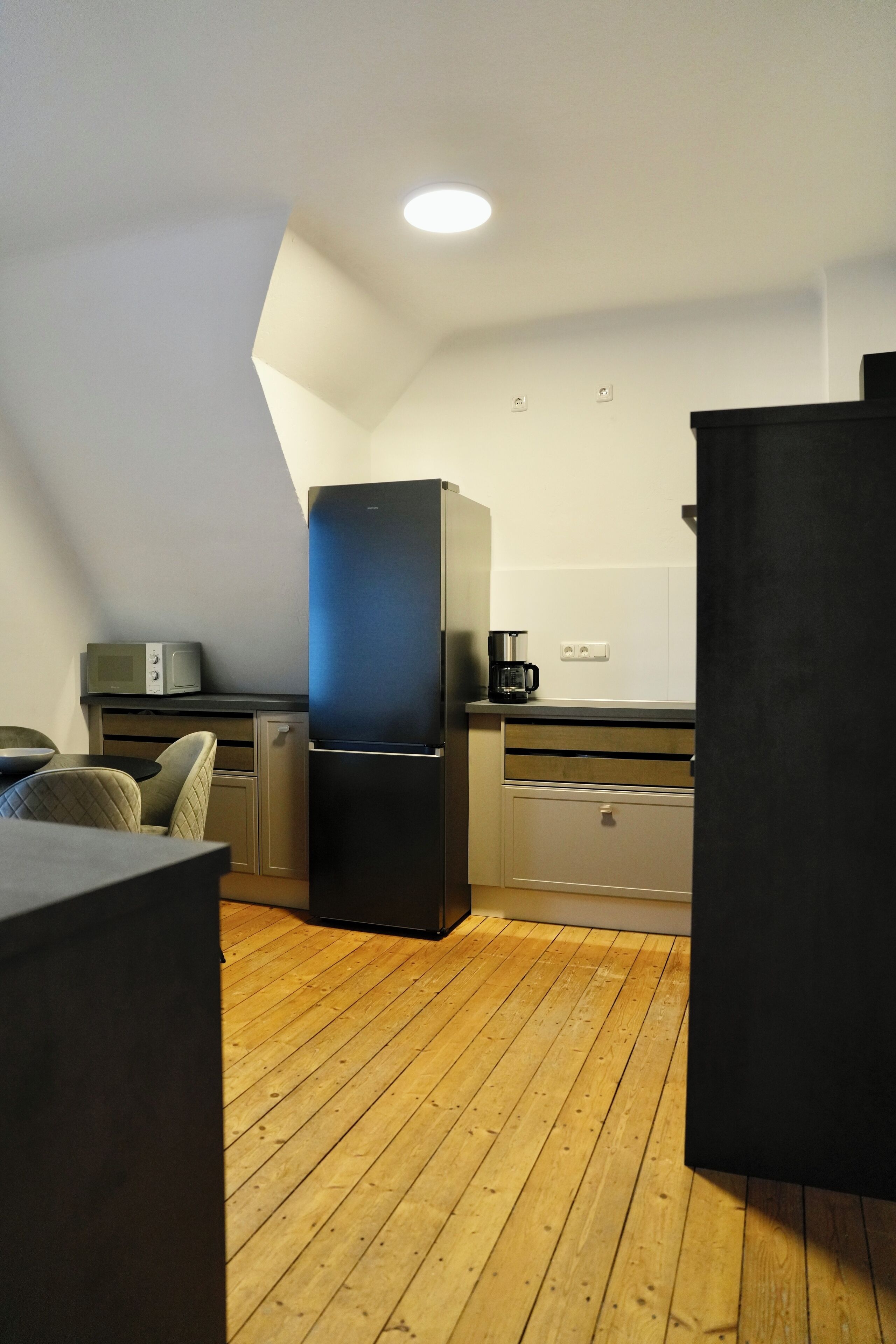 Una cocina compacta con refrigerador, microondas y cafetera sobre una encimera.