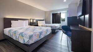 Ein Hotelzimmer mit zwei Betten, einem Schreibtisch, einem Stuhl und einem Fernseher.