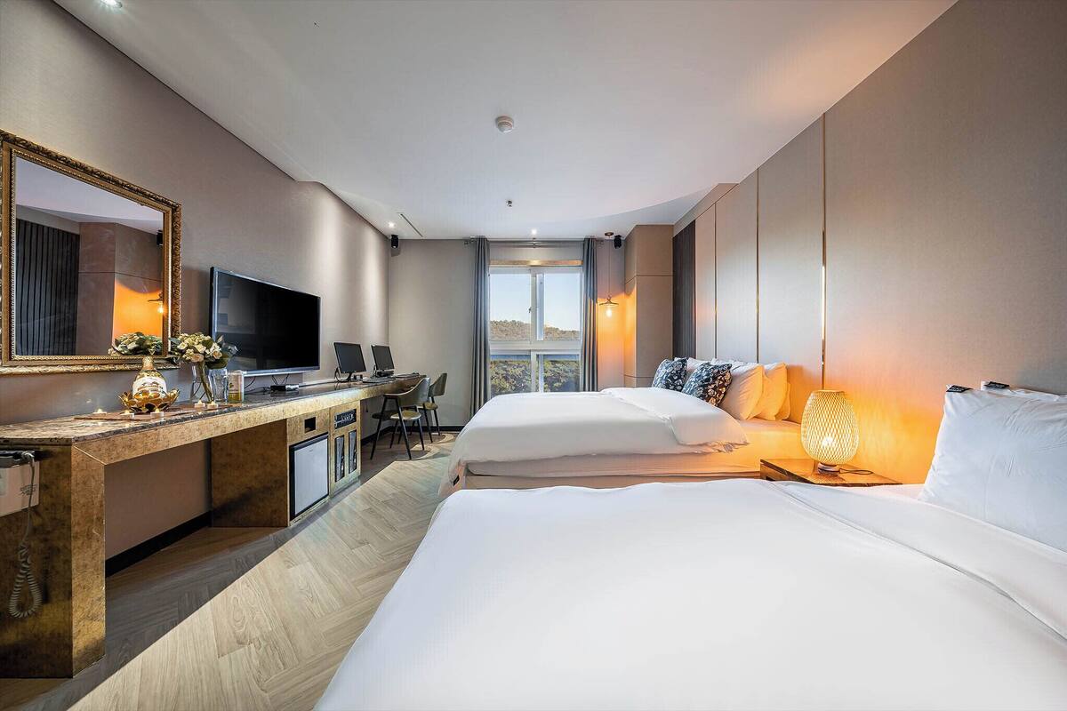 A hotel room with a large bed, a desk with a computer, a television, and a view of the outdoors.