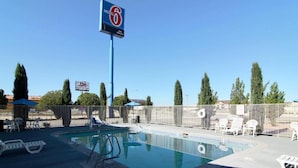 Un motel con piscina, sillas de descanso y un cartel que anuncia una ciudad divertida.