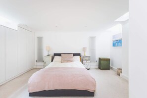 A bedroom with a bed, bedside tables, a radiator, a window, and a painting on the wall. - Parisian Style Duplex in Richmond Hill (Greater London)