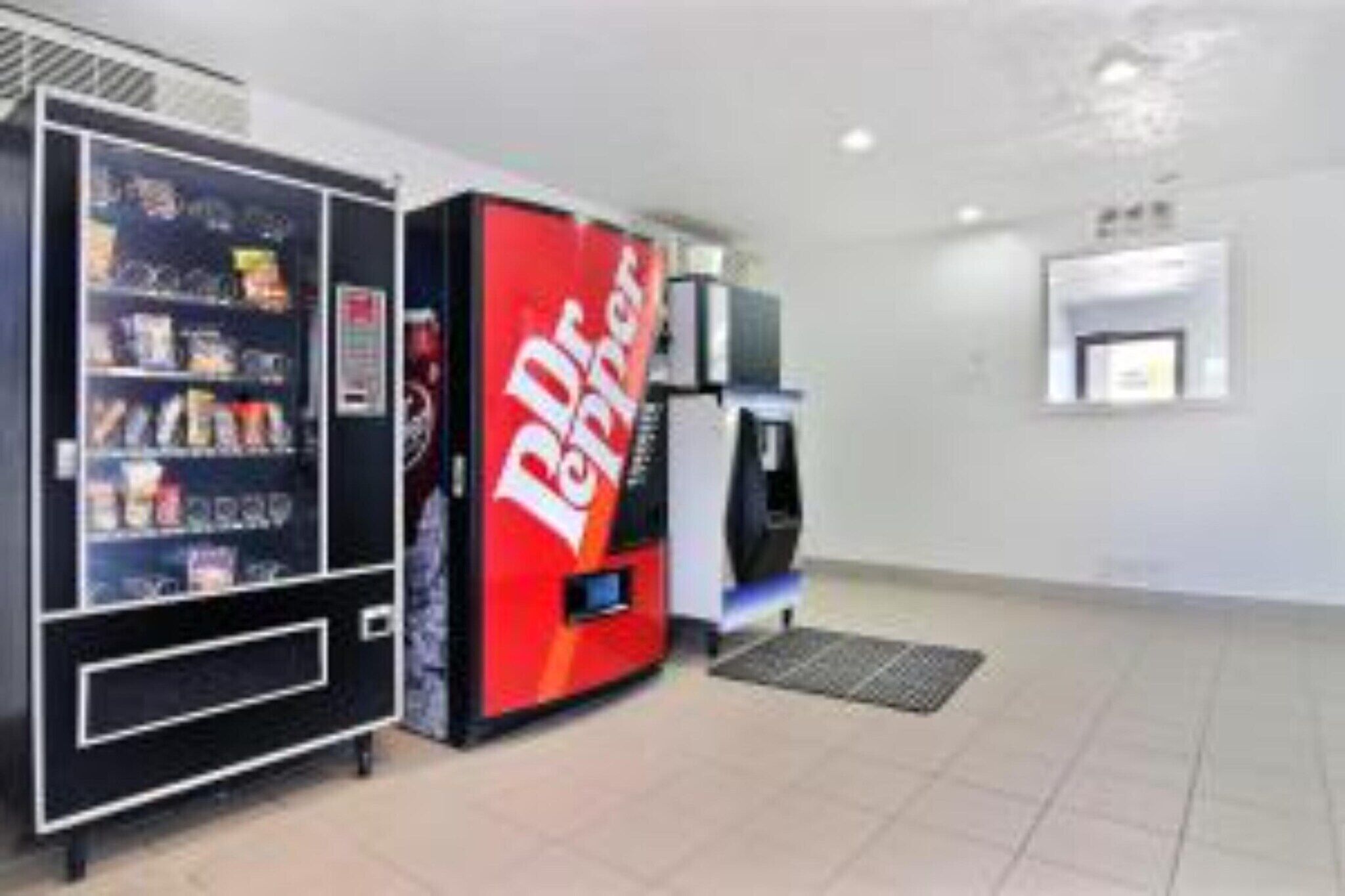 Zona de máquinas expendedoras con una máquina de Dr Pepper y un dispensador de bebidas.