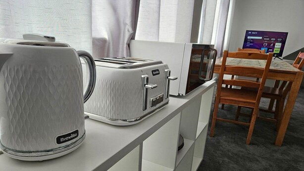 Eine Küchenzeile mit einem Breville-Toaster, einer Breville-Kaffeemaschine und einem Fernseher auf einem Tisch.