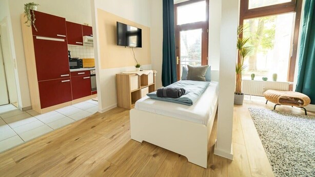 Ein modernes Schlafzimmer mit einem Bett, einem Fernseher, einem roten Kleiderschrank und einem Fenster mit Vorhängen.
