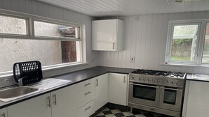 A kitchen with white cabinets, a black and white checkered floor, a gas stove, and a sink. - Standard Double Room (Belfast)
