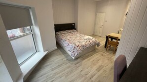 A bedroom with a bed, a window, a desk, and a chair. - Standard Double Room (Belfast)