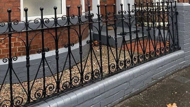 A brick building with a large window, a door with an arch, and a black wrought iron fence. - Standard Double Room (Belfast)