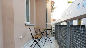 A balcony with two wooden folding chairs and a metal table, a tiled floor, and a metal fence. - FullHouse Apartments AB5 Medium (Halle (Saale))