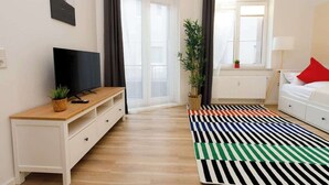 A modern living room with a TV, wooden cabinet, and a colorful striped rug. - FullHouse Apartments AB5 Medium (Halle (Saale))