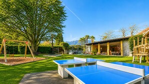 Un patio con mesas de ping pong, un columpio y un edificio con terraza.