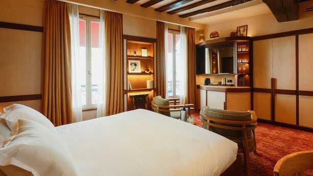 A hotel room with a large bed, wooden beams on the ceiling, a desk with a lamp, and a bookshelf. - Confidential Room 4, a stone's throw from the Louvre (Paris)