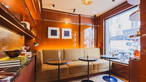 A cozy seating area with a sofa and two small round tables, a wooden interior, and a window with a view of the street. - Confidential Room 4, a stone's throw from the Louvre (Paris)