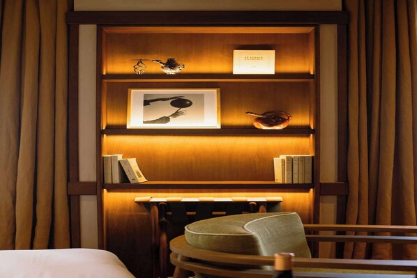 A hotel room with a wooden bookshelf, a framed picture, and a small table with a chair. - Confidential Suite 6, a stone's throw from the Louvre (Paris)