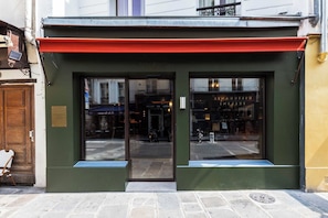 A building with a green facade, a red awning, and large glass doors. - Confidential Suite 6, a stone's throw from the Louvre (Paris)