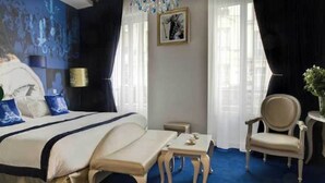Una habitación de hotel con una cama grande, una mesita de noche, una silla y una pequeña mesa.