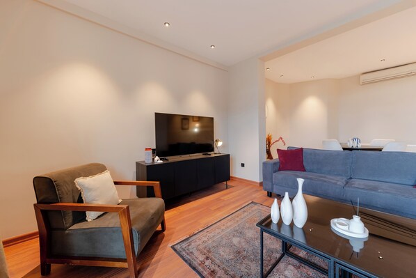 A modern living room with a sofa, armchair, and a flat-screen TV on a black stand. - The Best in Beyoglu–Galata Tower View – Elevator – Renovated Interior – Balcony (İstanbul)