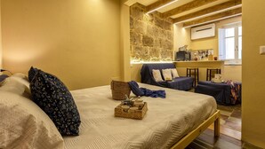 Une pièce confortable avec un lit, un mur en pierre, un petit coin cuisine et une fenêtre.