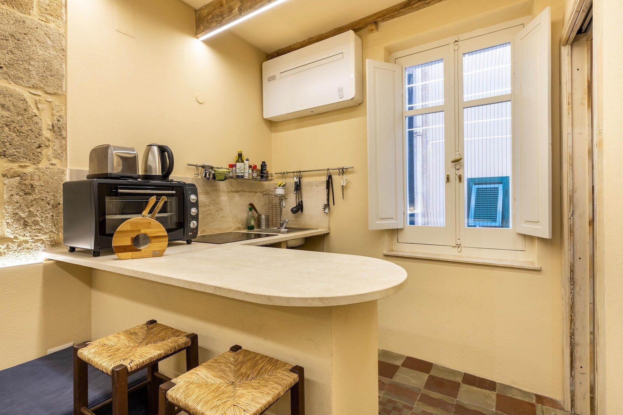 Una cucina compatta con tostapane integrato, macchina da caffè e un piccolo bancone con sgabelli.