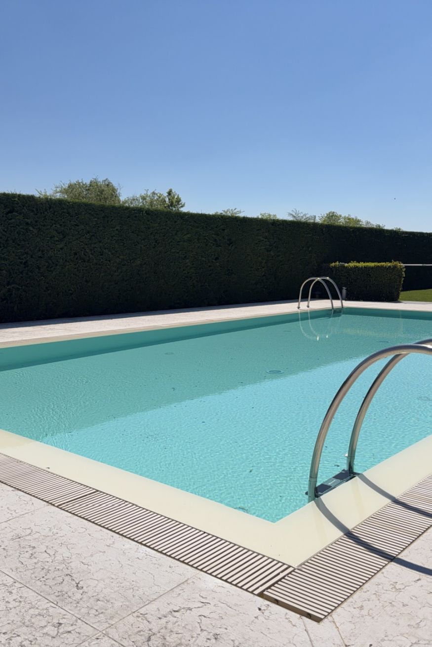 A swimming pool with a metal ladder and a tiled deck.