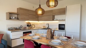 A modern kitchen with wooden cabinets, a dining table set for six, and pendant lighting. - 10 Min Walk from the Beach, Free Swimming Pool (Peschiera del Garda)