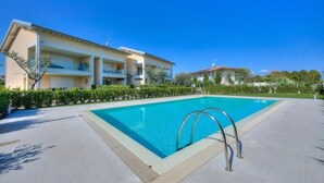 A swimming pool with a metal ladder, surrounded by a paved area and a building with balconies. - 10 Min Walk from the Beach, Free Swimming Pool (Peschiera del Garda)