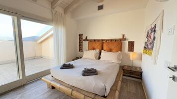 Ein Schlafzimmer mit einem großen Bett, einer Glastür zum Balkon und einem Holzkopfteil.