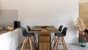 A dining area with a wooden table, black chairs, and a coffee machine on the counter. - Apartment with air conditioning and terrazzo (Castelsardo)