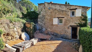 Un bâtiment rustique en pierre, avec une allée en gravier et un banc en bois.