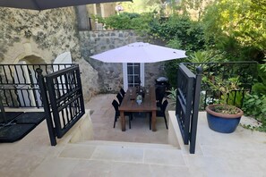 A patio with a table and chairs, a large umbrella, and a potted plant. - Beautiful Detached Villa with Pool (Flayosc)