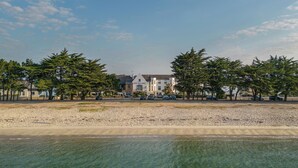 Un albergo con un grande edificio, un'area di parcheggio e una spiaggia sullo sfondo.