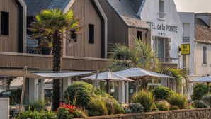 Un hotel con facciata moderna, sedute all'aperto con ombrelloni e un curato giardino.