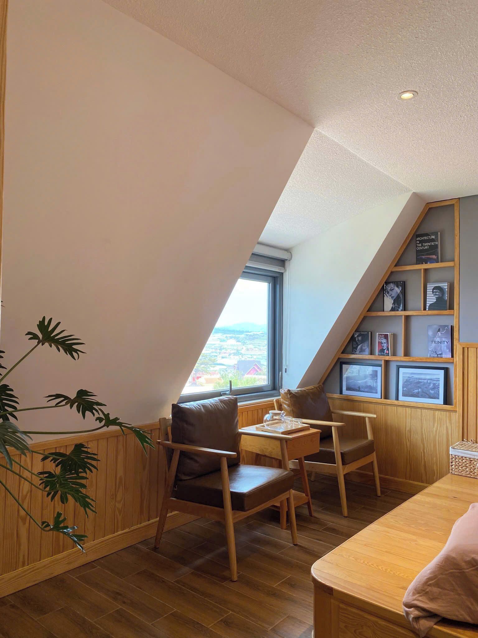 Un rincón acogedor con una mesa y sillas de madera, una planta en maceta y una estantería con fotografías enmarcadas.
