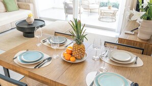 Een eettafel gedekt met borden, bestek, wijnglazen, een ananas en sinaasappels.